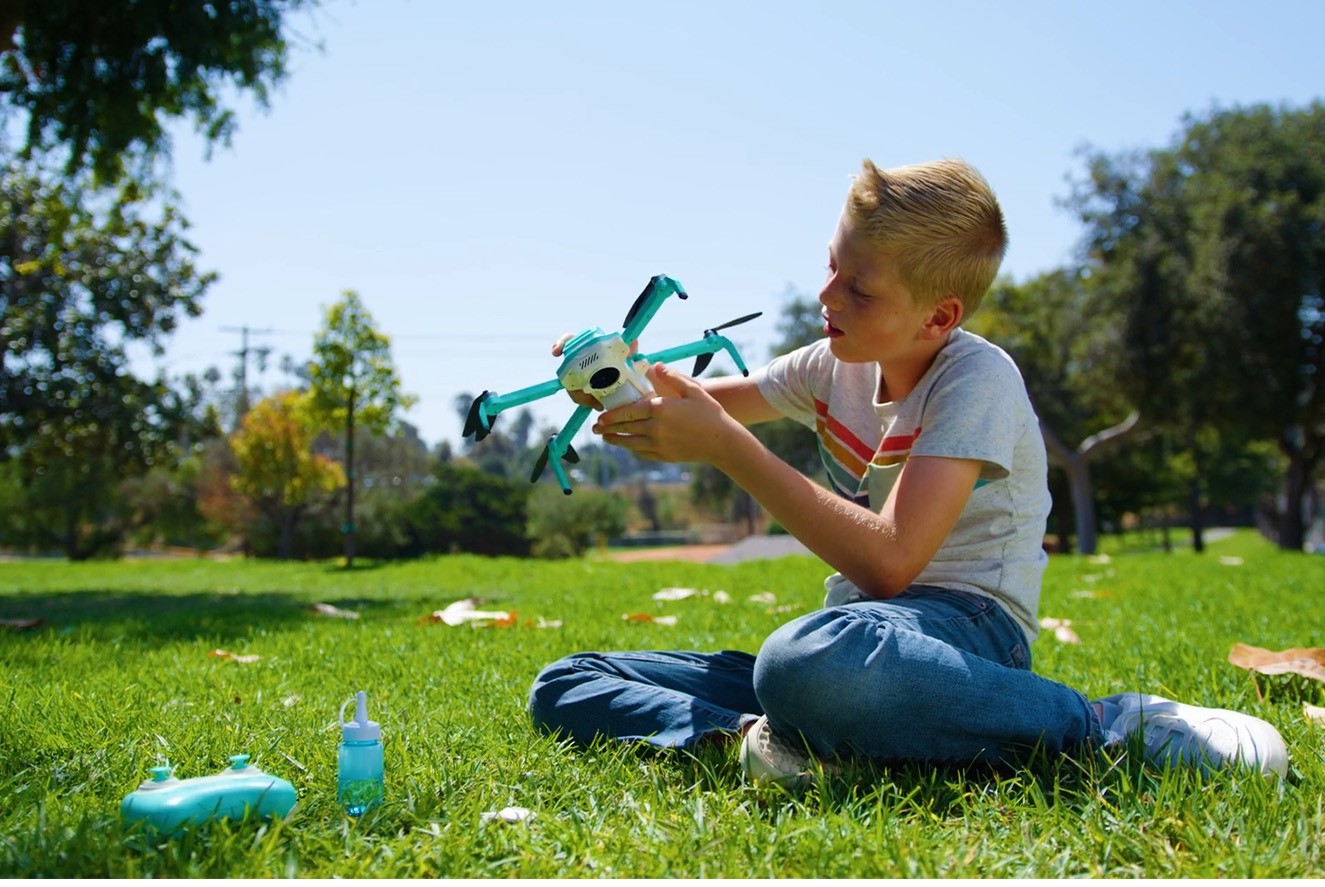 Child holding and exploring the HS320 flying bubble drone outdoors